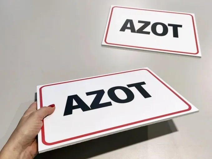 Tabliczka Azot - Wzór graficzny. Prosta tabliczka z napisem AZOT w dużych, czarnych literach na białym tle z czerwoną ramką