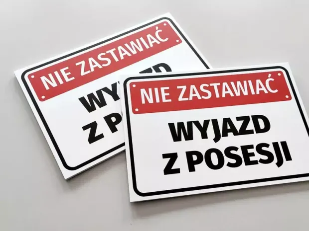 Tabliczka Nie zastawiać, wyjazd z posesji - Wzór graficzny. Prosta forma, duży czarny tekst na białym tle, czerwone elementy