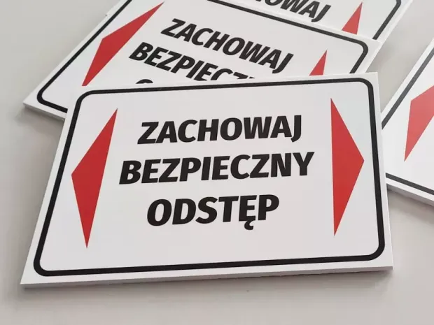 Tabliczka Zachowaj bezpieczny odstęp - Wzór graficzny. Prostokątna tabliczka z białym tłem, czerwonymi strzałkami i czarnym
