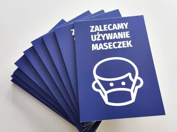 Tabliczka Zalecamy używanie maseczek - Wzór graficzny. Niebieskie tło z białym piktogramem twarzy w maseczce