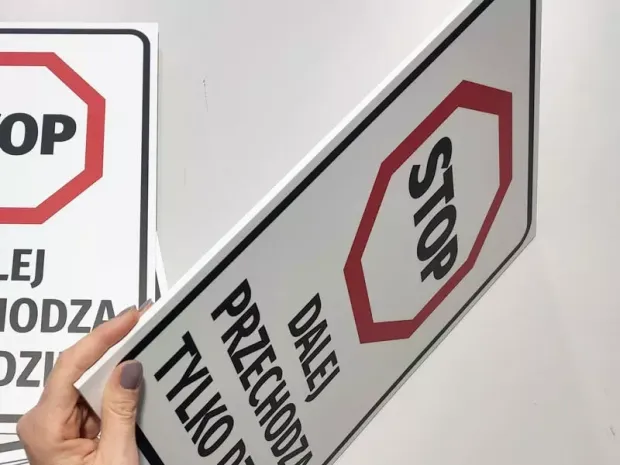 Tabliczka BHP Stop dalej przechodzą tylko dzieci trzymana w dłoni, pokazująca lekkość i grubość płyty spienionej