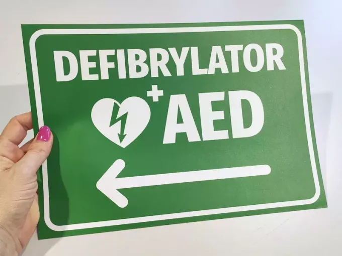 Naklejka Defibrylator AED N561 - Wzór graficzny. Zielone tło z białym napisem i symbolem serca oraz strzałką