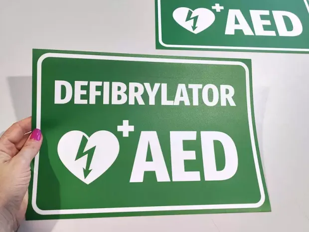 Naklejka Defibrylator AED N562 - Wzór graficzny. Zielone tło z białym napisem i symbolem serca z błyskawicą