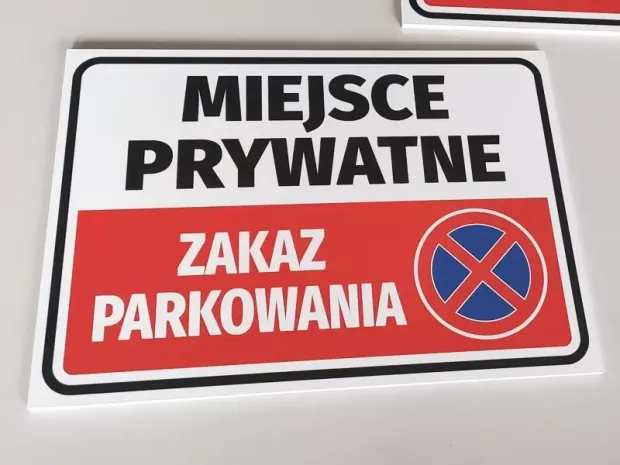 Tabliczka Miejsce prywatne Zakaz parkowania leżąca na płaskiej powierzchni, pokazująca grubość płyty