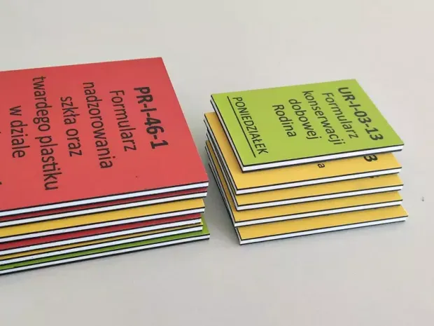 Dwustronne magnesy z rdzeniem PCV ułożone w stosy, prezentujące różne kolory tła przykładowego nadruku