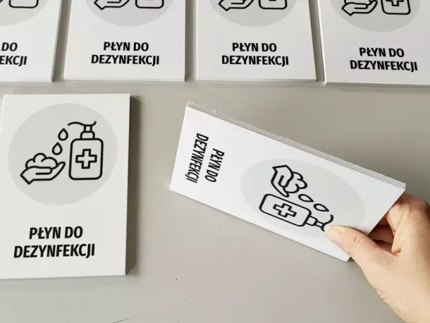 Tabliczka Płyn do dezynfekcji T480 - Wzór graficzny. Grafika przedstawia butelkę z płynem, ręce i symbol krzyża