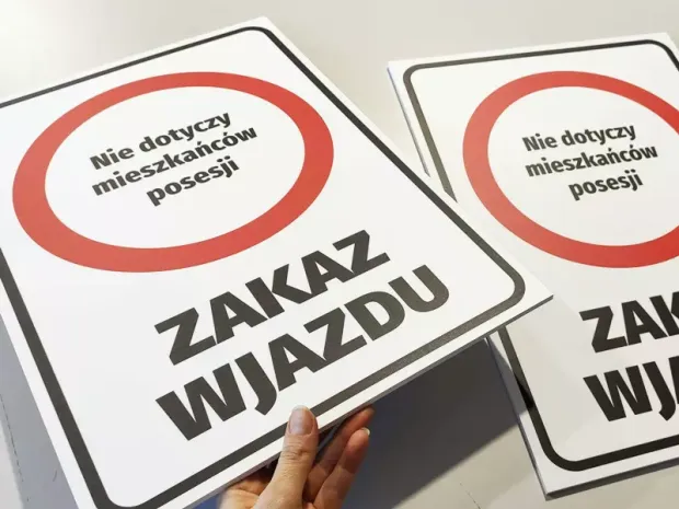 Dwie sztywne tabliczki Zakaz wjazdu - Nie dotyczy mieszkańców posesji w ujęciu pokazującym grubość płyt