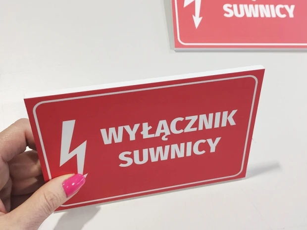 Czerwona tabliczka BHP Wyłącznik suwnicy w ujęciu prezentującym grubość i biały rdzeń płyty spienionej PCV