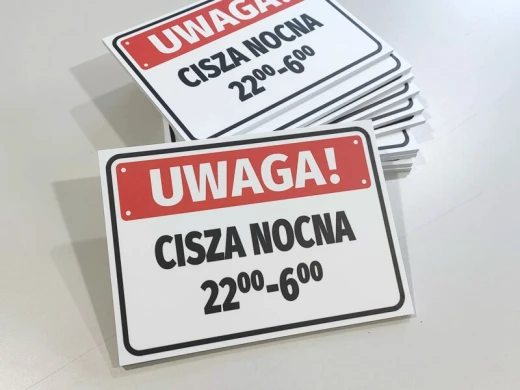 Stos tabliczek informacyjnych Uwaga Cisza nocna 22:00-6:00 w ujęciu pokazującym grubość sztywnej płyty