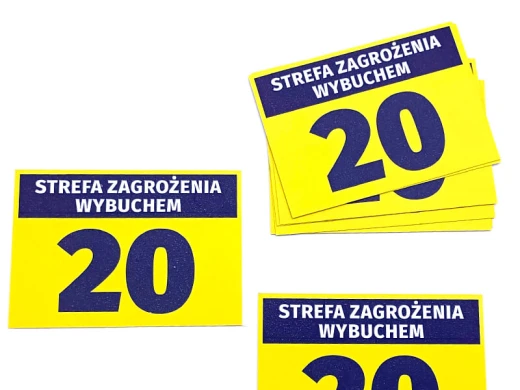 Żółte naklejki BHP Strefa zagrożenia wybuchem 20 z czarnym napisem, pokazane w stosie i jako osobne sztuki