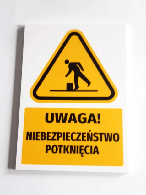 Tabliczka ostrzegawcza BHP z piktogramem Uwaga! Niebezpieczeństwo potknięcia - Wzór graficzny. Posiada trójkątny kształt