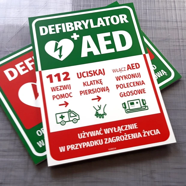 Tabliczka Defibrylator AED z instrukcją pomocy - Wzór graficzny. Prostokątna tabliczka z zielonym tłem, białymi i czerwonymi