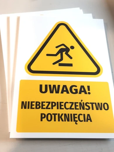 Żółta tabliczka ostrzegawcza BHP Uwaga Niebezpieczeństwo potknięcia w stosie kilku gotowych sztuk