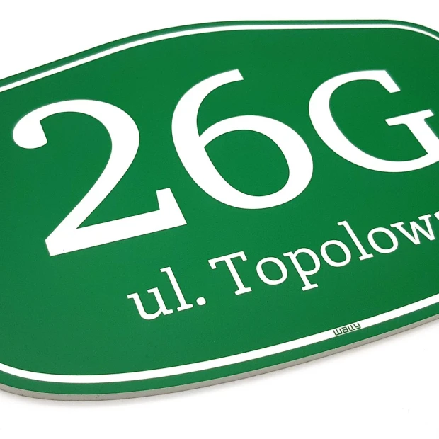 Zielona tabliczka adresowa w zbliżeniu pokazującym grubość płyty i przykładowe pole na numer oraz ulicę