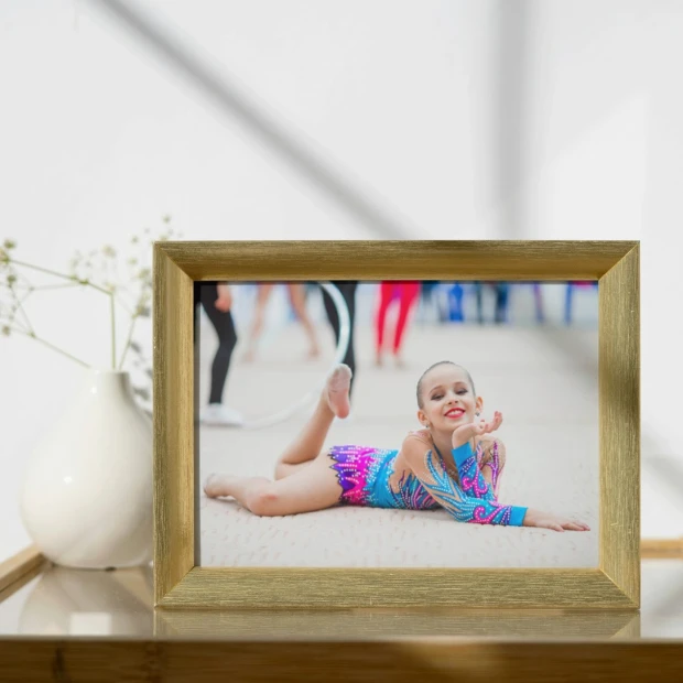 Fotoplakat z pojedynczą fotografią przedstawiającą gimnastyczkę, zaprezentowany w ramce we wnętrzu