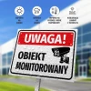 Tabliczka Uwaga obiekt monitorowany - Wzór graficzny. Prostokątna tabliczka z czarnym napisem na białym tle, z symbolem