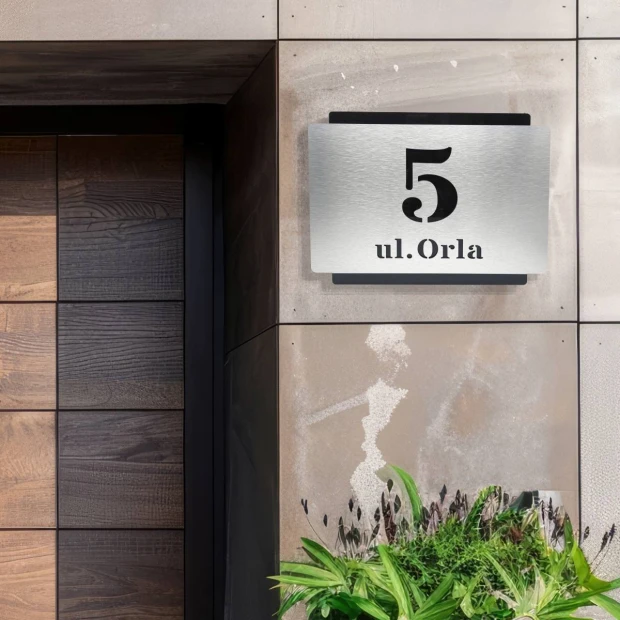 Tabliczka adresowa z dibondu zamontowana na elewacji przy drzwiach, z polem na numer domu i nazwę ulicy