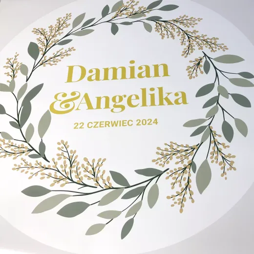 Okrągła naklejka ścienna z przykładowym nadrukiem roślinnego wianka oraz miejscem na personalizowany podpis
