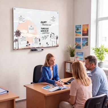 Tablica suchościeralna z grafiką palm i notatkami na ścianie w biurze podróży nad biurkiem z obsługiwaną parą.